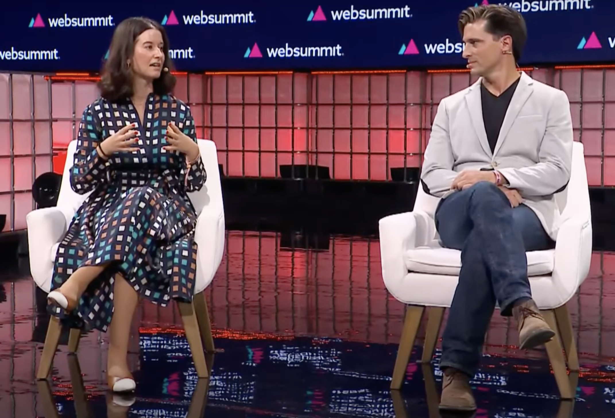 Cristina Fonseca (à esquerda) e Vasco Pedro (à direita) no palco da Web Summit 2023 sentados em cadeiras. Cristina está a gesticular enquanto fala.
