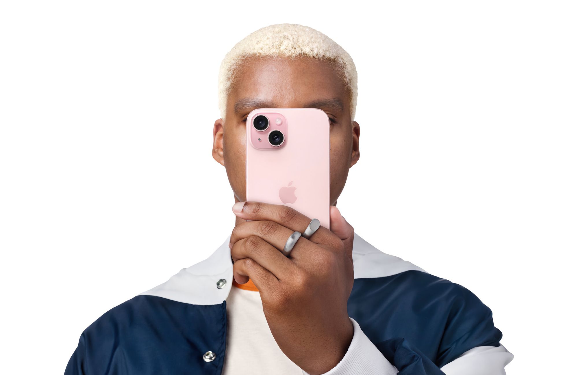 Pessoa a pegar num iPhone 15 com a mão esquerda e a tapar a cara com o mesmo.