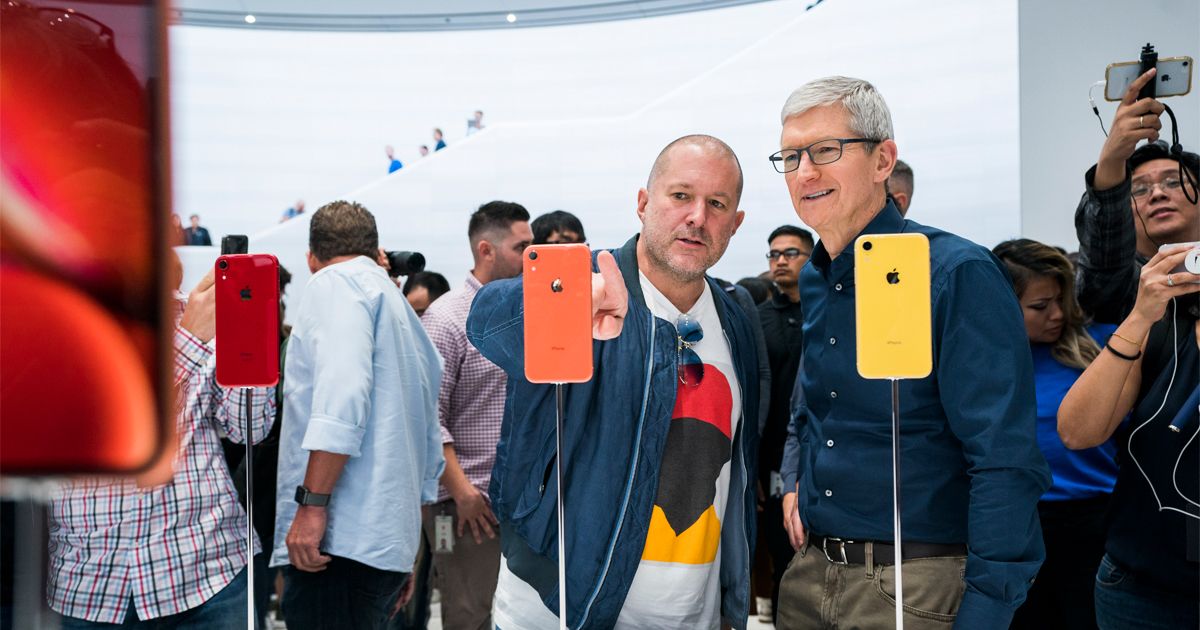 Jony Ive ao lado de Tim Cook a apontar para um iPhone com vários outros em montra e muitas pessoas à volta.