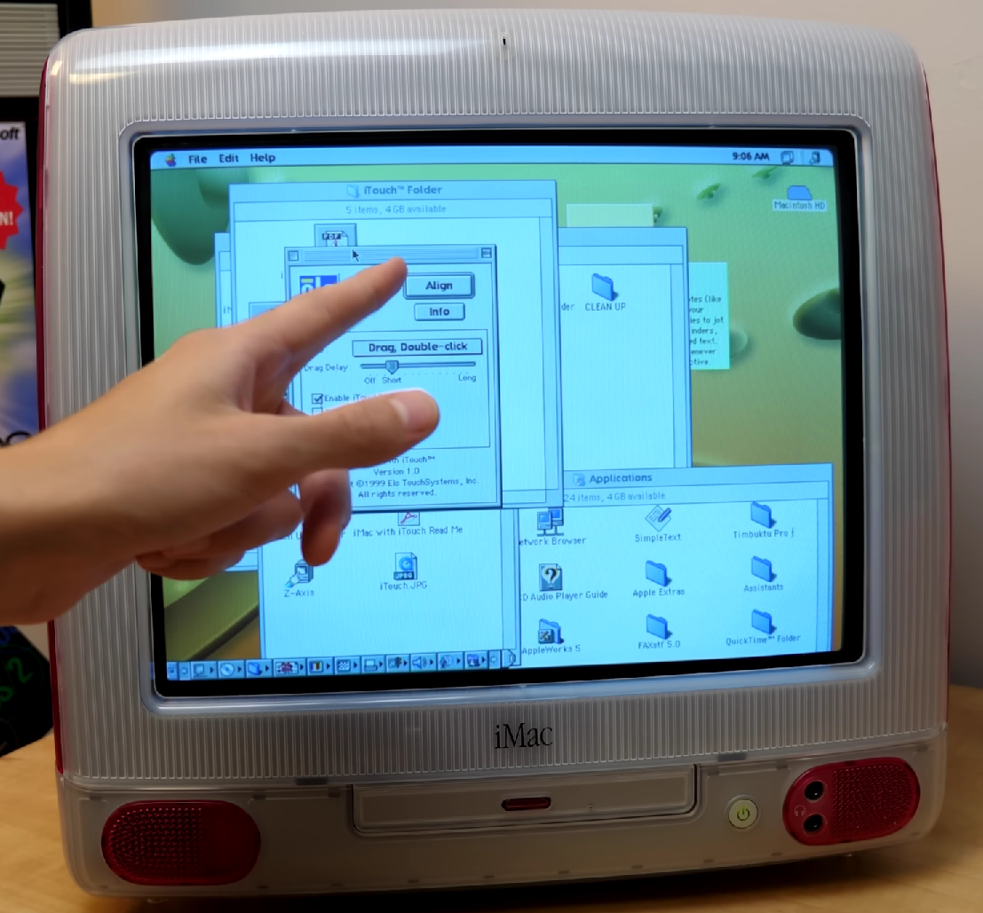 Dedo a tocar no ecrã tátil de um iMac G3 de 1999.