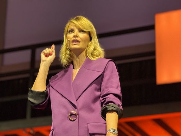 Cristina Ferreira no palco 3 da Web Summit 2023, com o braço direito levantado, ao nível do pescoço.